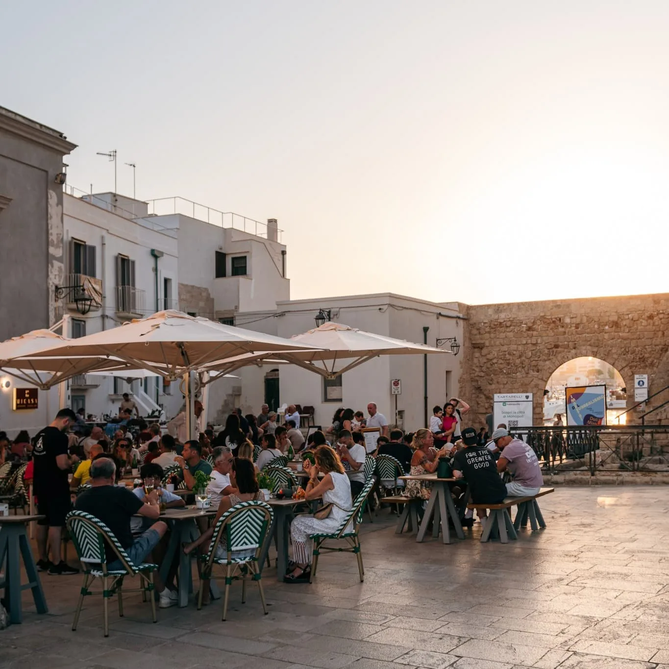 tables and umbrellas outside tamborr italian pizzeria restaurant by the city walls of monopoli puglia italy
