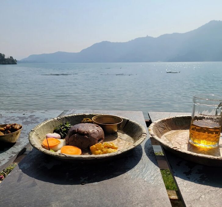 Plates of Nepalese meals overlooking a lake