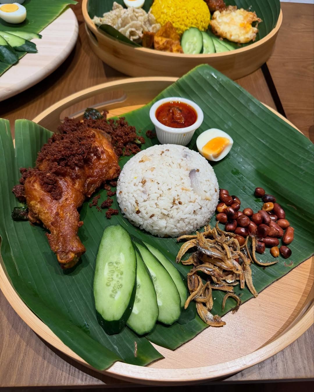 Nasi lemak with coconut rice, boiled egg, cucumber slices, peanuts, fried anchovies, and fried chicken