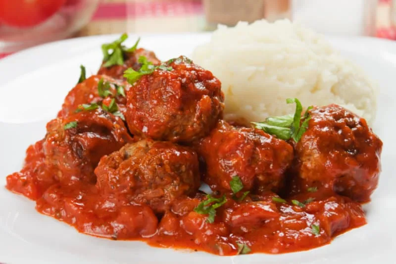 chiftele cu puire are a traditional meatball from moldova served in tomato sauce over mashed potatoes