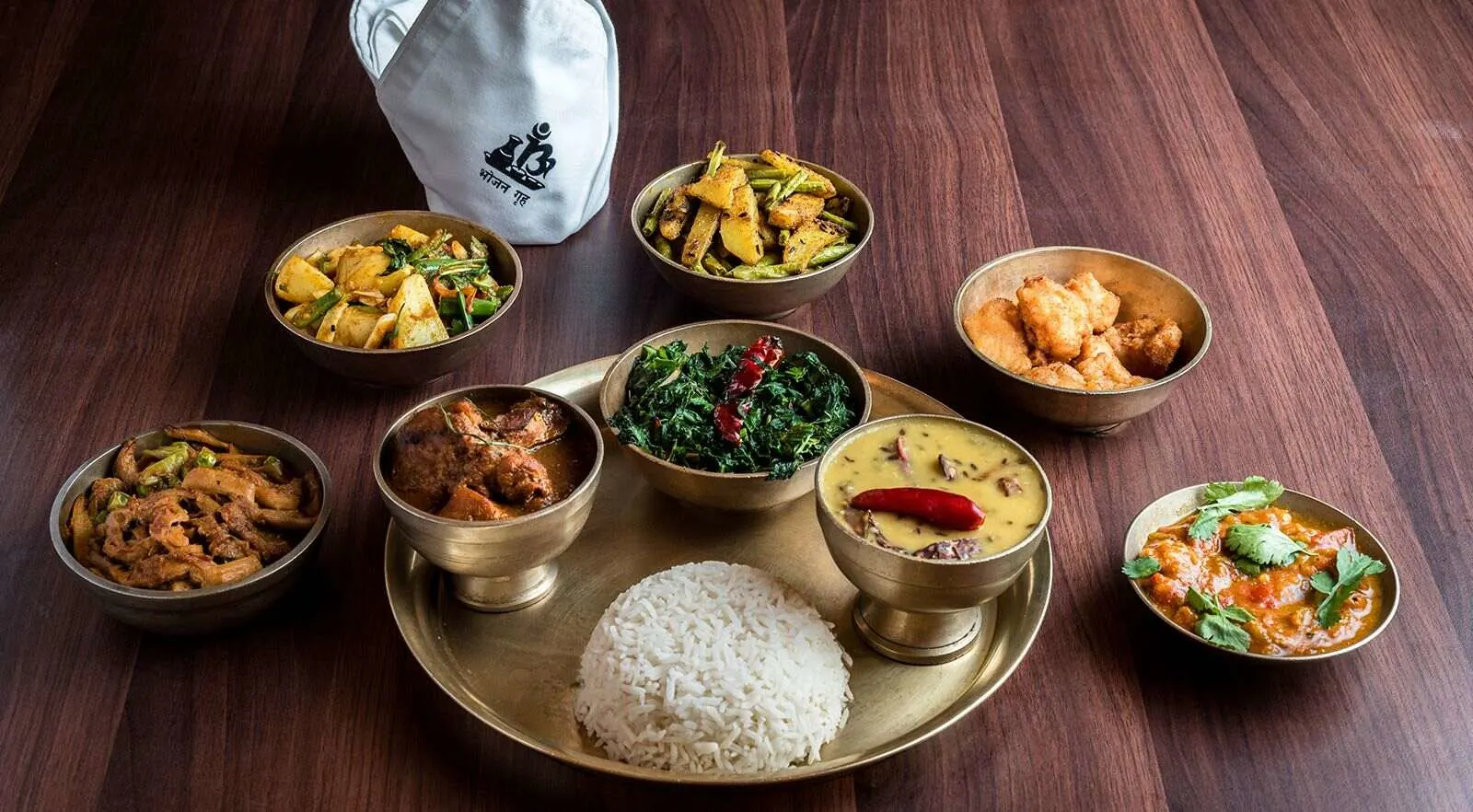 A Nepalese meal served in traditional brass plates and bowls
