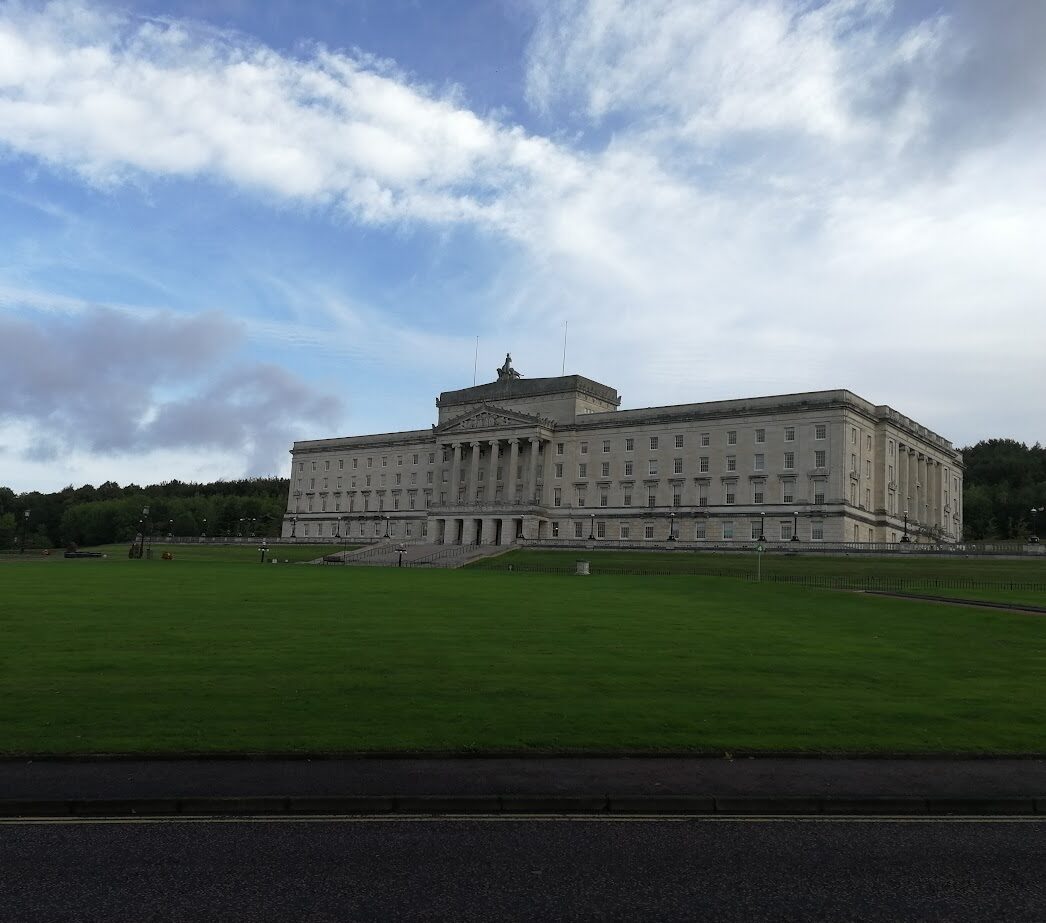 a large stone building with a grass expanse in front is stormont home of the northern ireland assembly in belfast