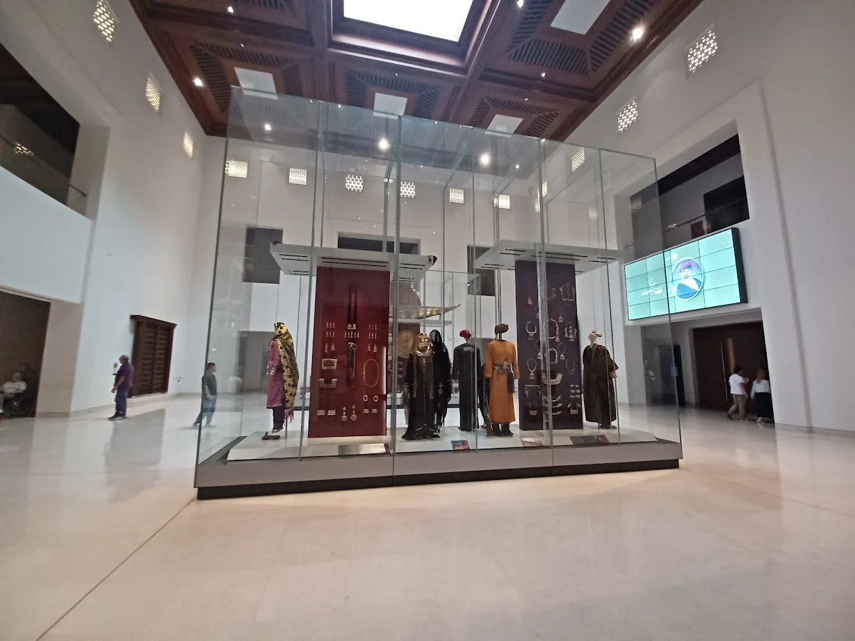 a display of omani garments in a glass cabinet at the national museum of oman in muscat