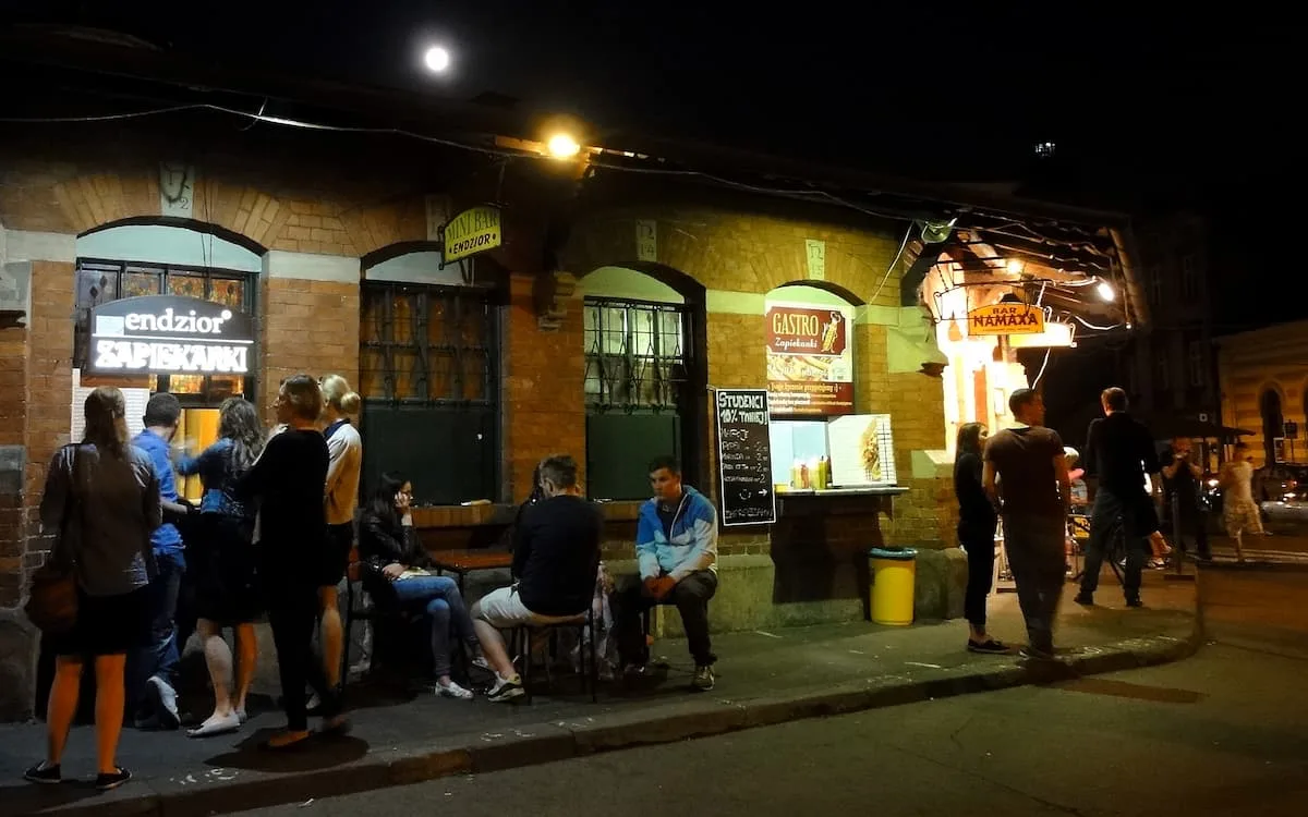 a brick building with a serving hatch selling zapiekanka on a dark night in krakow poland