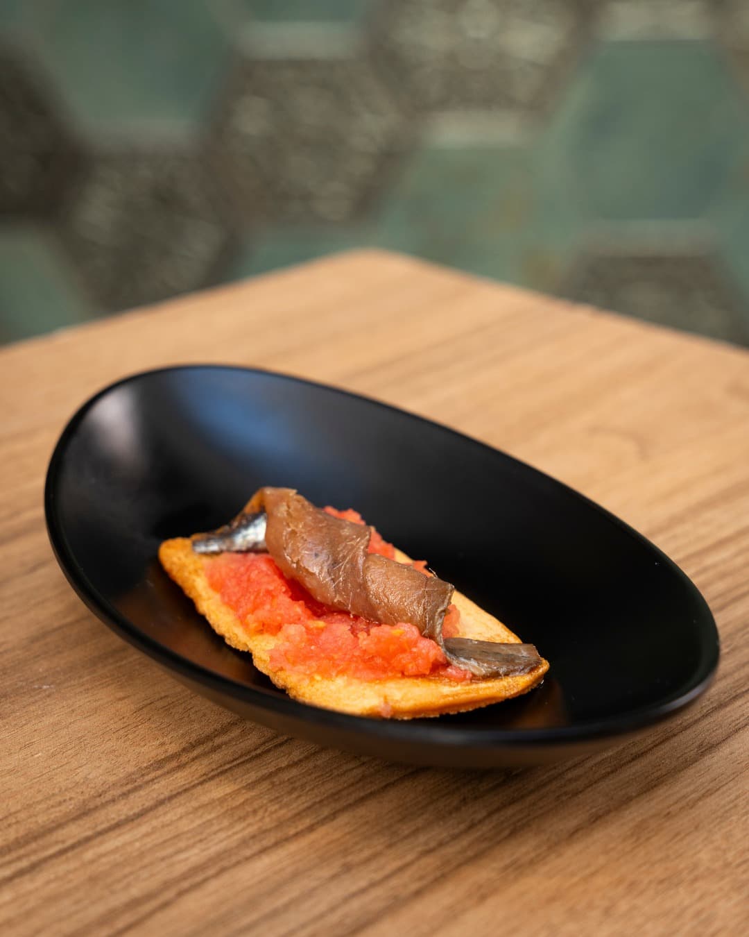 Classic tomato tostada with a rolled anchovy fillet
