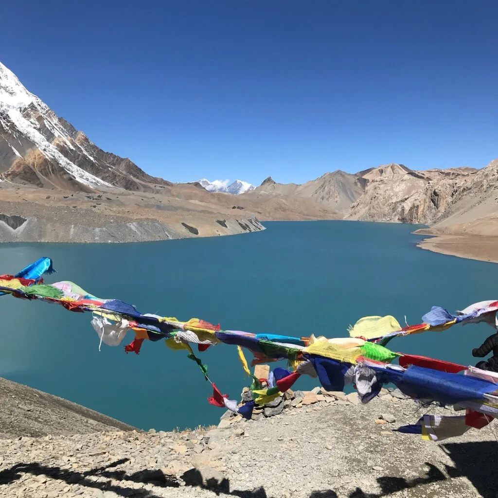 Tilicho Lake surrounded by colorful prayer flags 