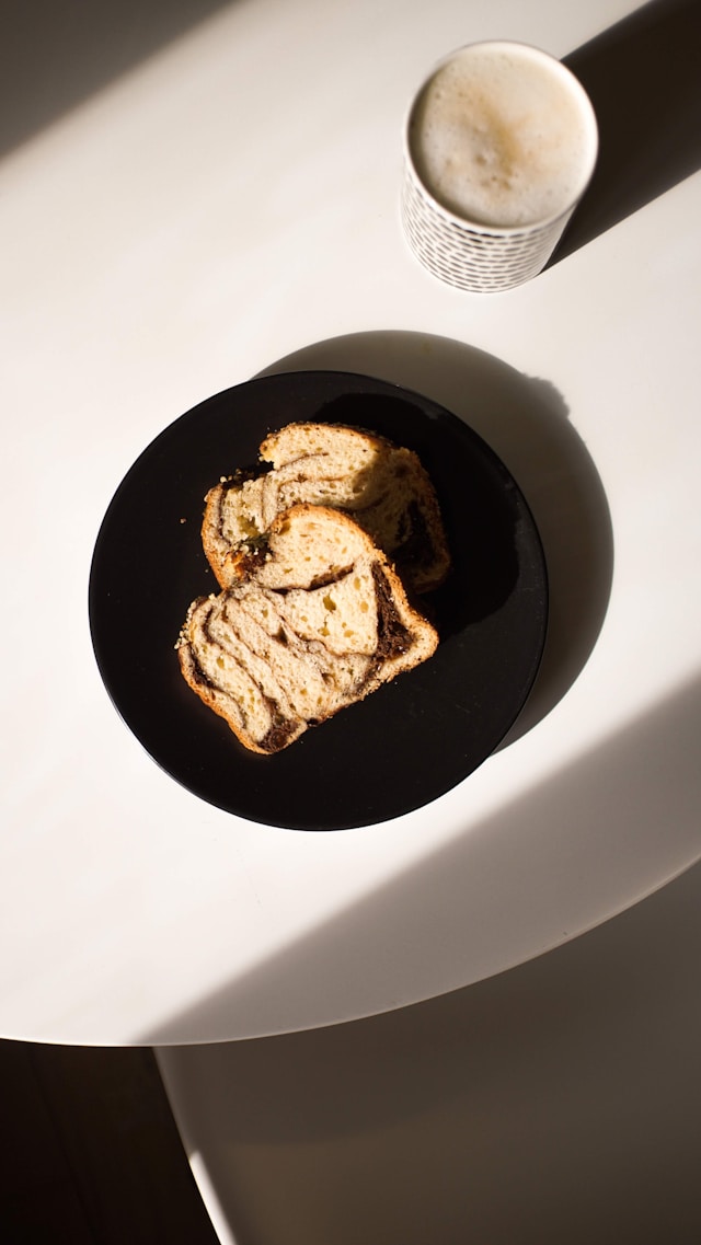 cozonac, a sweet bread, popular as a traditonal food in moldova on a black plate with a mug of coffee in the background