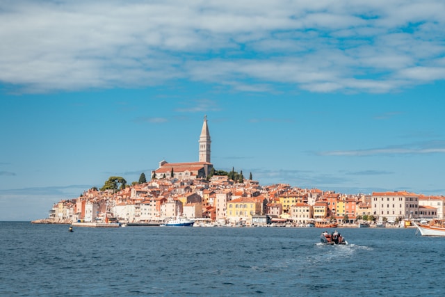 houses with red roofs with a tower in the background and the adriatic in the foreground in rovinj croatia