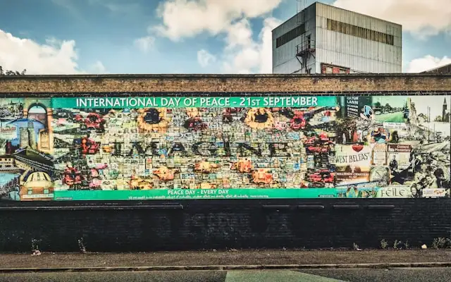 a mural on the peace wall in belfast northern ireland with a high-rise tower block in the background