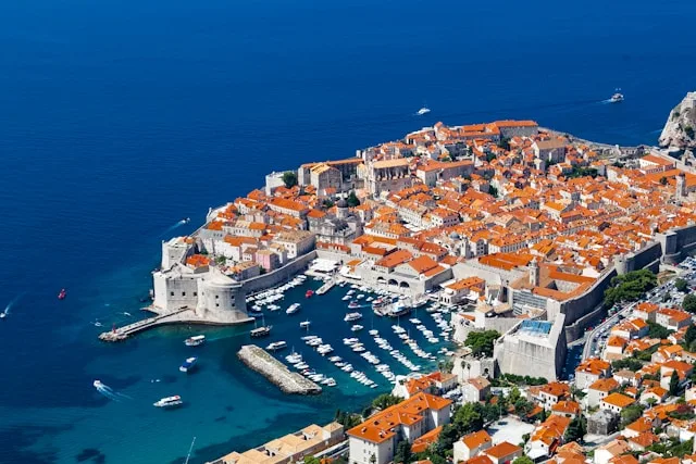 red rooftops of dubrovnik old town with a marina in the foreground and the adriatic sea in the background in dubrovnik croatia