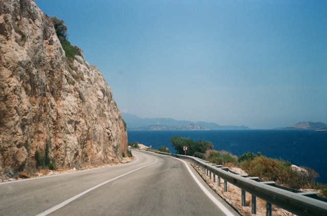 an empty road with the ocean ahead and a cliff to the left in italy