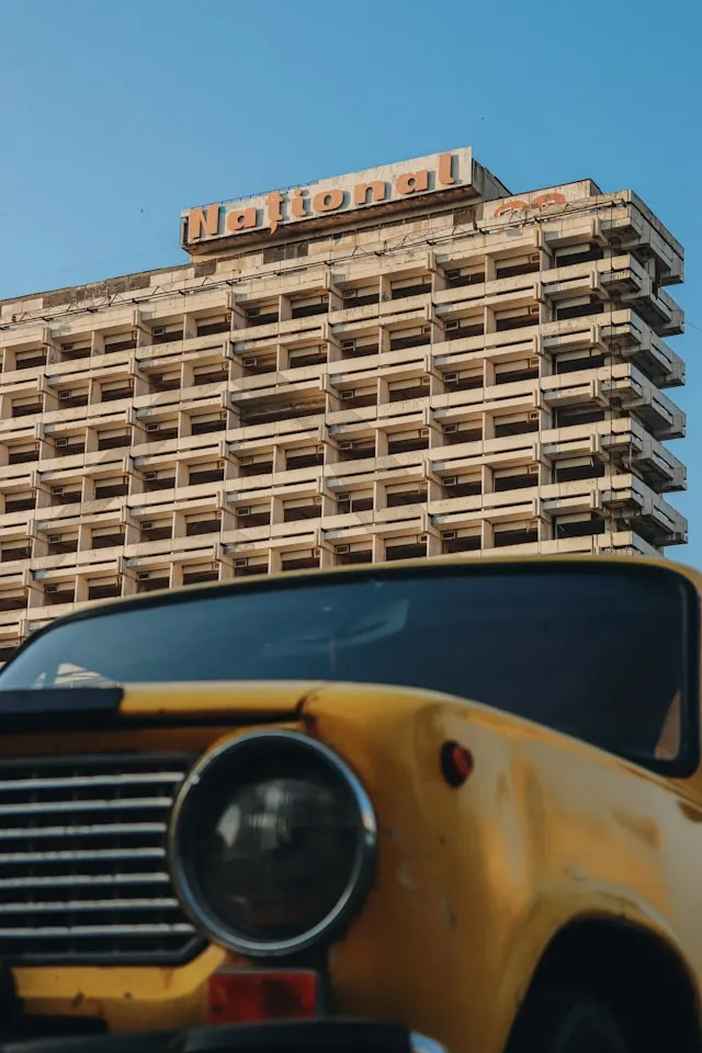 a rusting yellow car in front of an abandoned soviet tower block in chisinau moldova