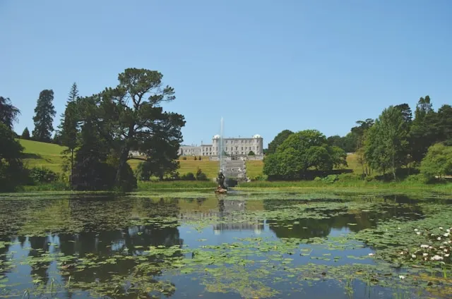 a lake with lilies in front of powerscourt house in wicklow ireland