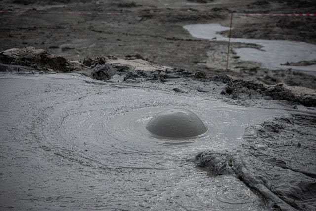 a hole in the ground with mud erupting from it at the mud volcanoes complex in gilinj azerbaijan