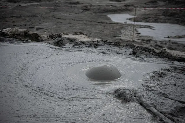 a hole in the ground with mud erupting from it at the mud volcanoes complex in gilinj azerbaijan