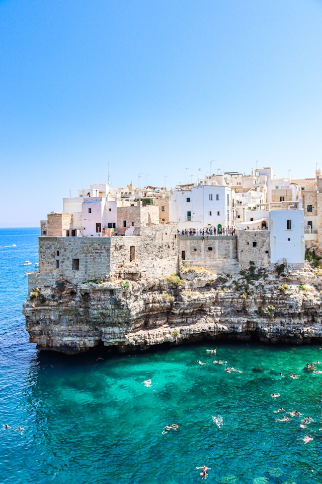 whitewashed houses behind a turquoise ocean in puglia itlay