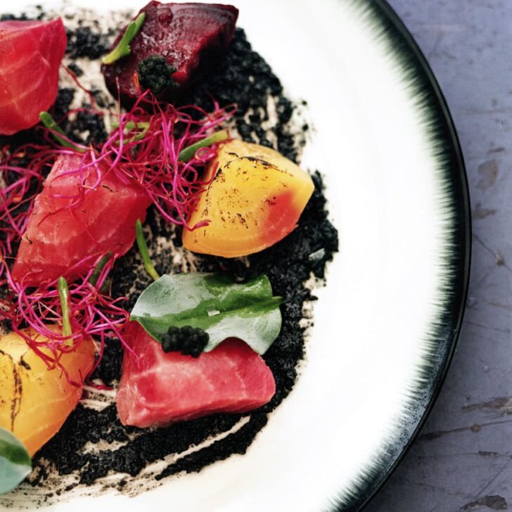 a white plate with a black rim containing a colorful salad from and/or vegan restaurant in antwerp belgium