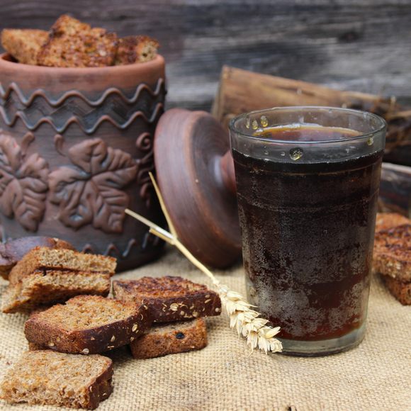 a glass of kali with rye bread at the side and a brown bread basket in the background in estonia