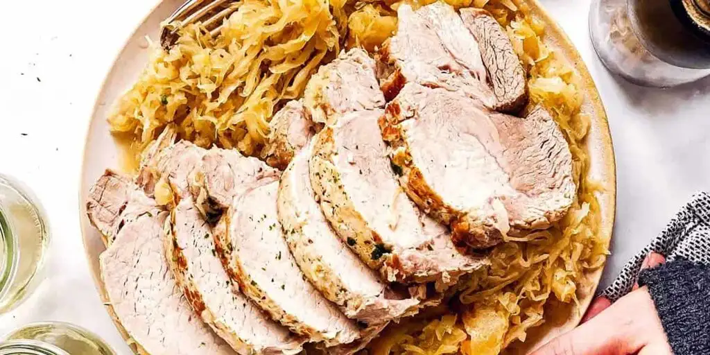 a plate of thickly sliced roast pork on a bed of sauerkraut