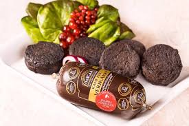 blood sausage in a wrapper with slices of verikakk and a garnish in the background