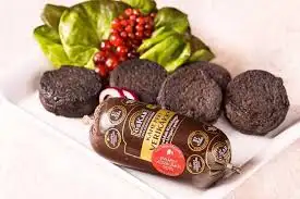 blood sausage in a wrapper with slices of verikakk and a garnish in the background