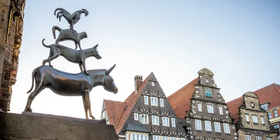 The statue of the Town Musicians next to old buildings of Bremen