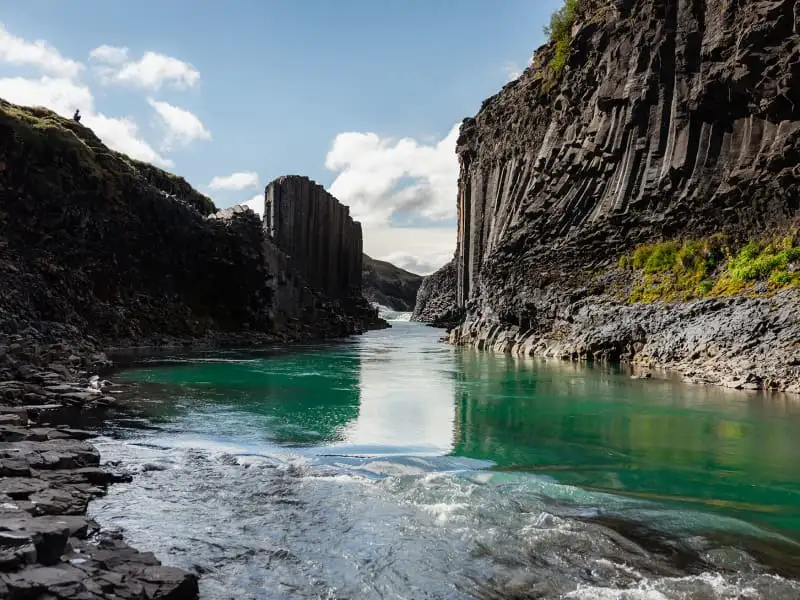 a waterfall drops into a fjord surrounded by cliffs in eglisstadir iceland