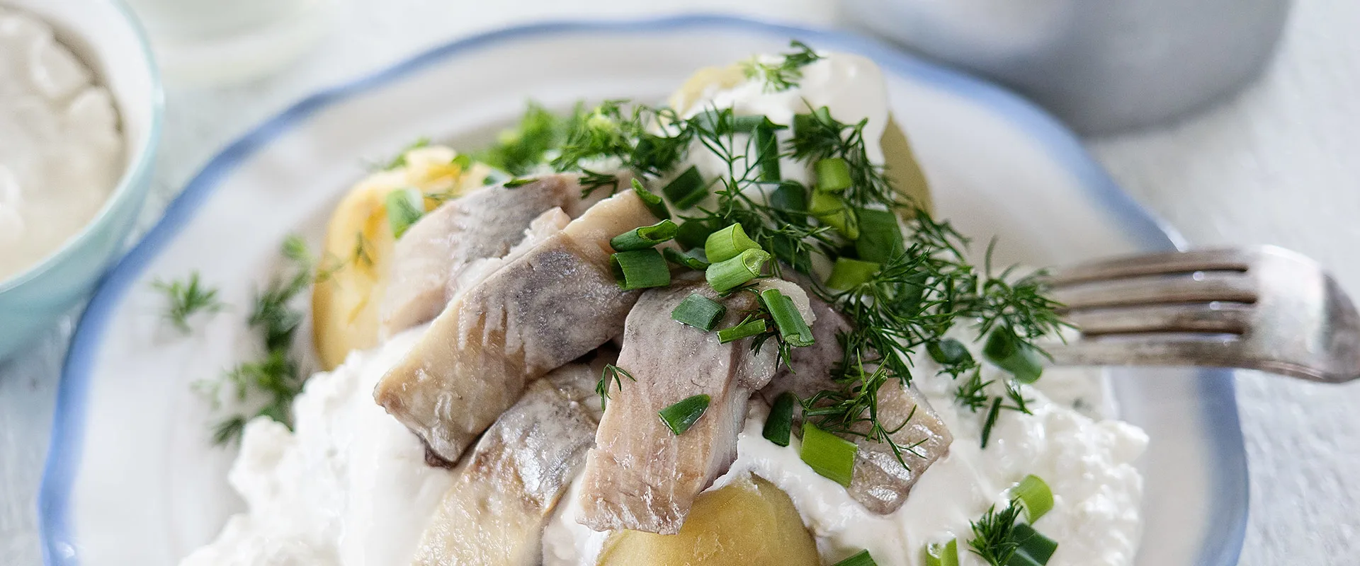 Biezpiens ar Kartupeļiem, Siļķi un Zaļumiem is a latvian dish of herring served on top of potatoes and cottage cheese with sour cream