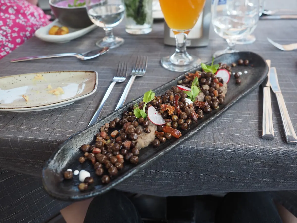 a black rectangular plate with latvian national dish peleki zirni ar speki at a restaurant in riga latvia