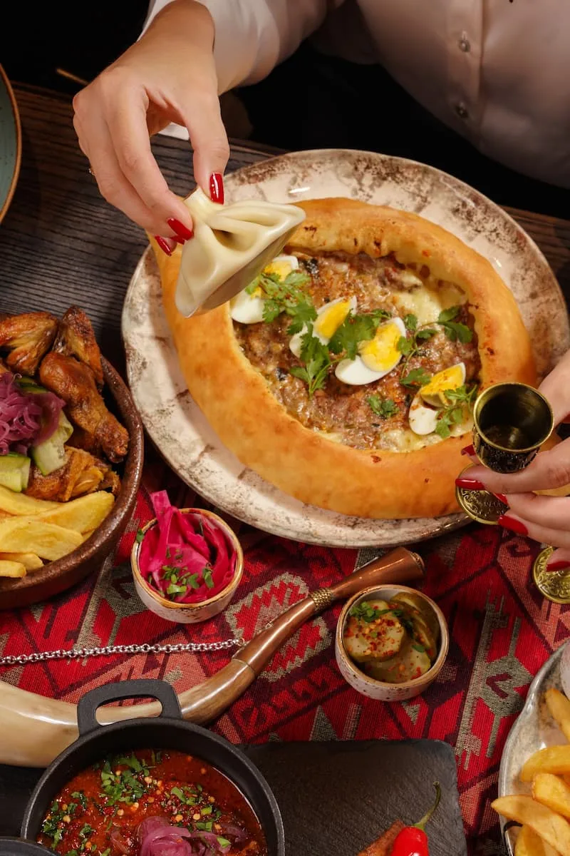 a table containing traditional georgian food including khachapuri and khinkali at hacapuri bistro in riga latvia
