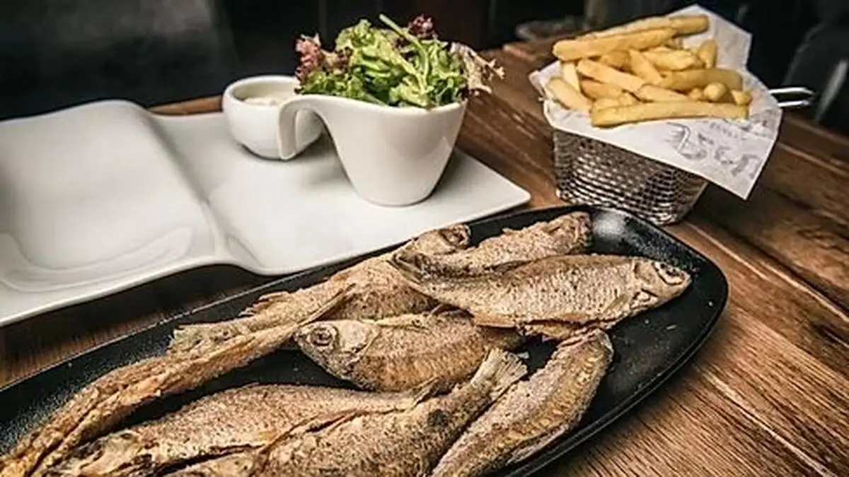 a black dish with whole fried small fish known as friture de la moselle which is a luxembourg traditional food