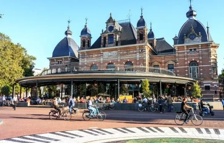 A view of Arnhem street with people riding their bicycles and a historic building in the background