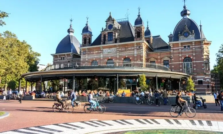 A view of Arnhem street with people riding their bicycles and a historic building in the background