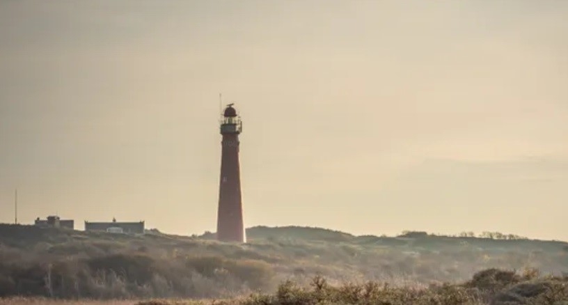A lighthouse on a dune-covered beach
