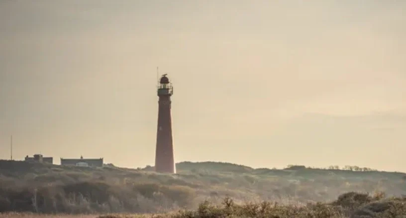 A lighthouse on a dune-covered beach