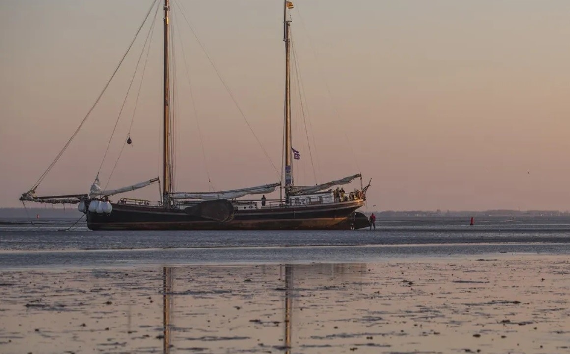 A sailboat by mud flats