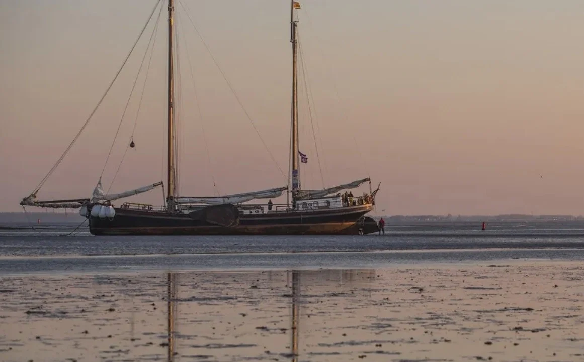 A sailboat by mud flats