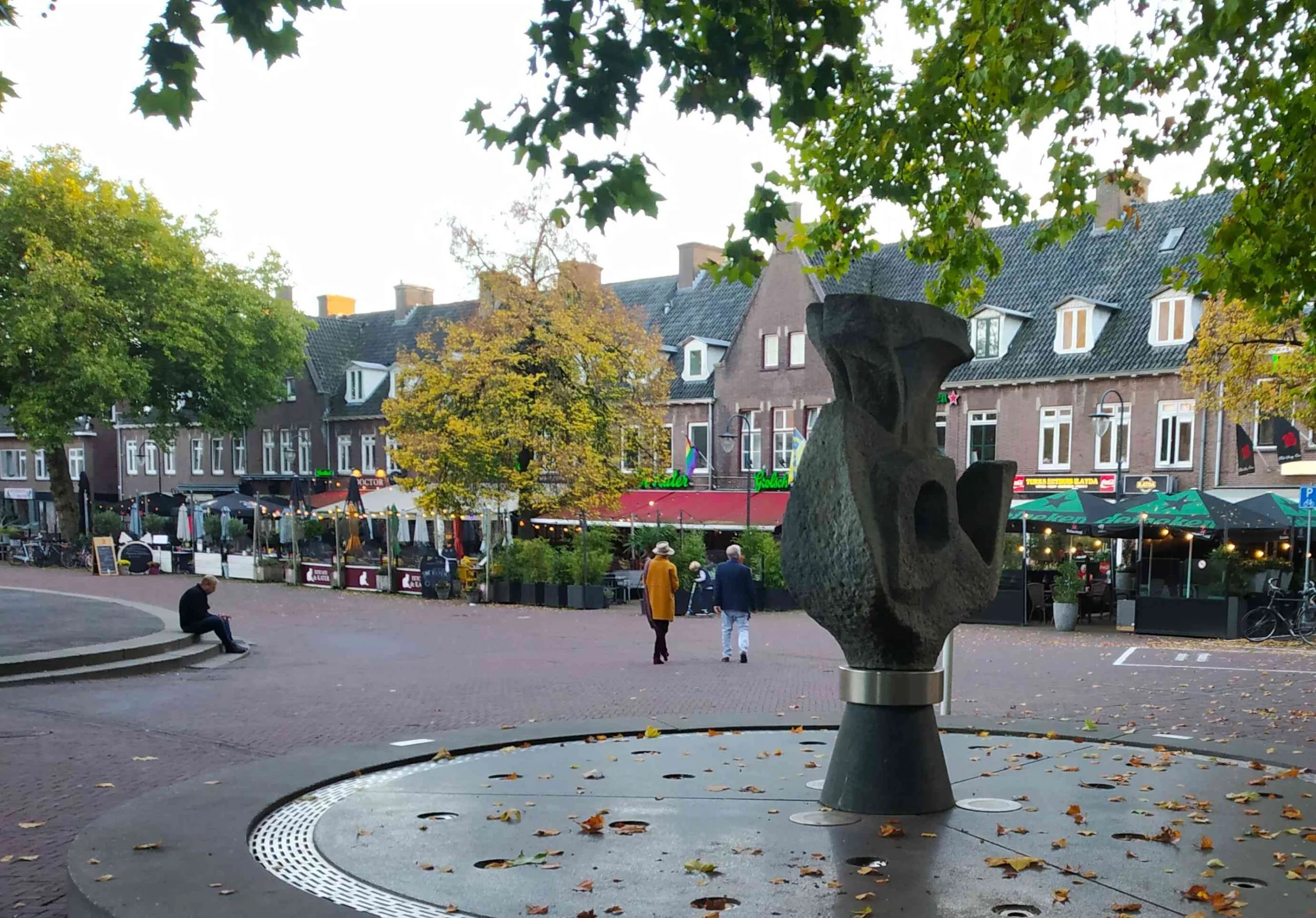 A town square with a fountain and cafés surrounding it