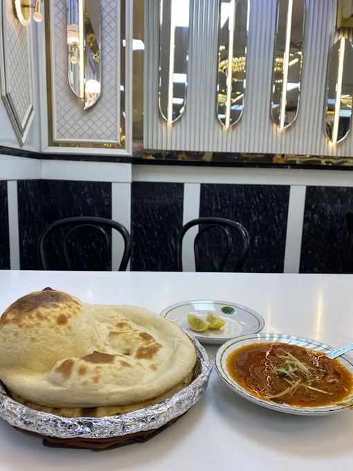 Plate of naan bread next to a bowl of Nihari stew