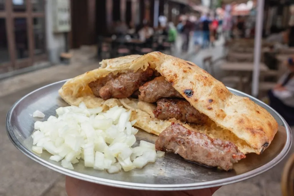 a metal tray with grilled meat kebab known as cevapi in serbia and onions