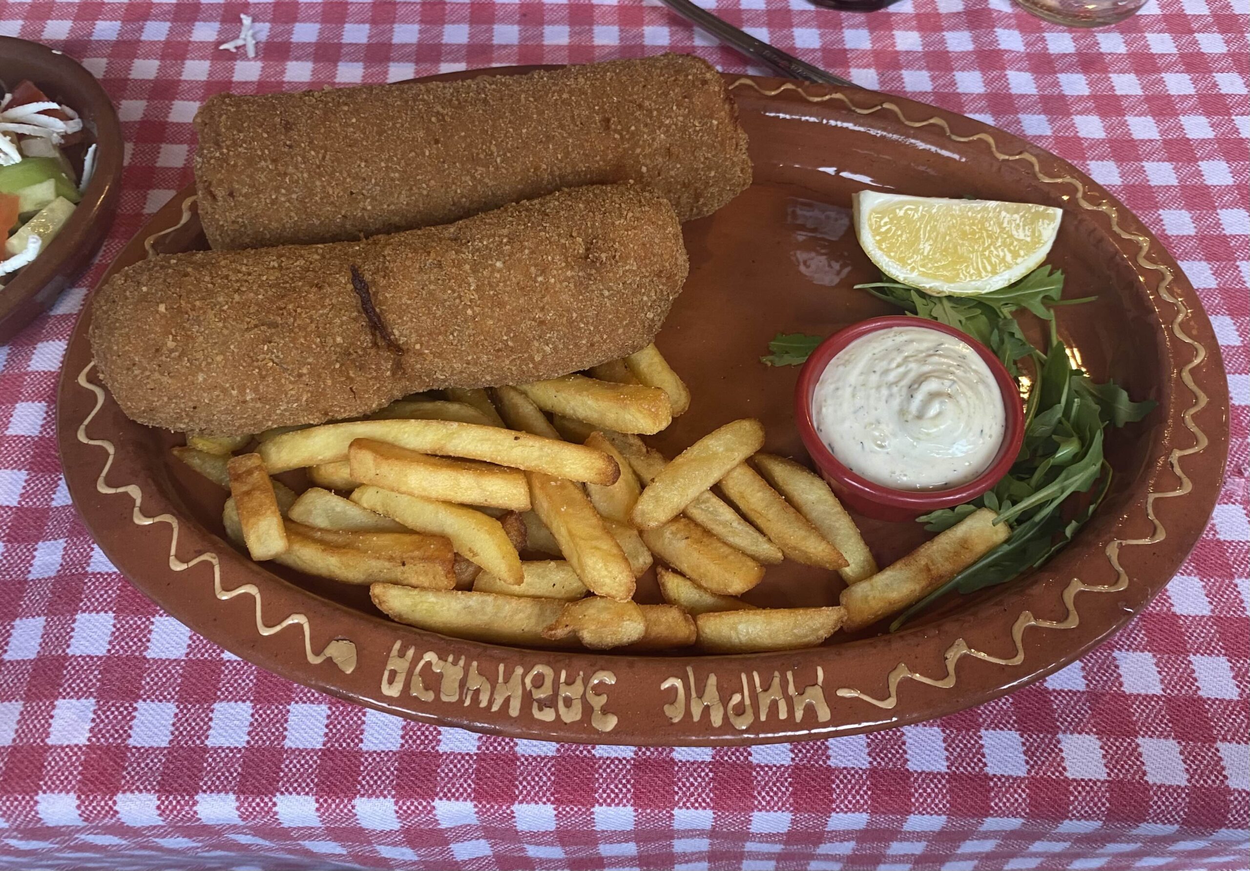 a red plate on a check table cloth with Karadordeva Snicla and french fries in serbia
