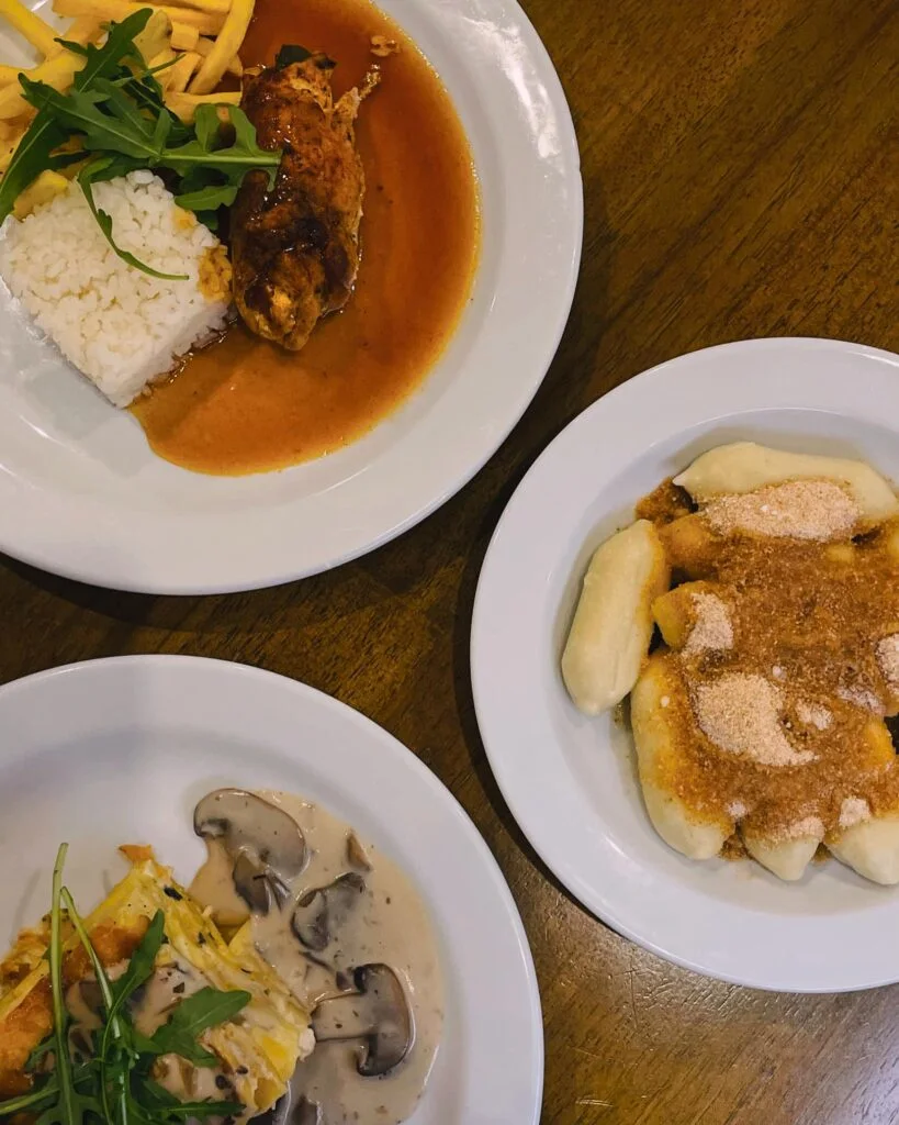 three white plates containing slovakian food including the national dish bryndzove halusky from marco restaurant in poprad slovakia