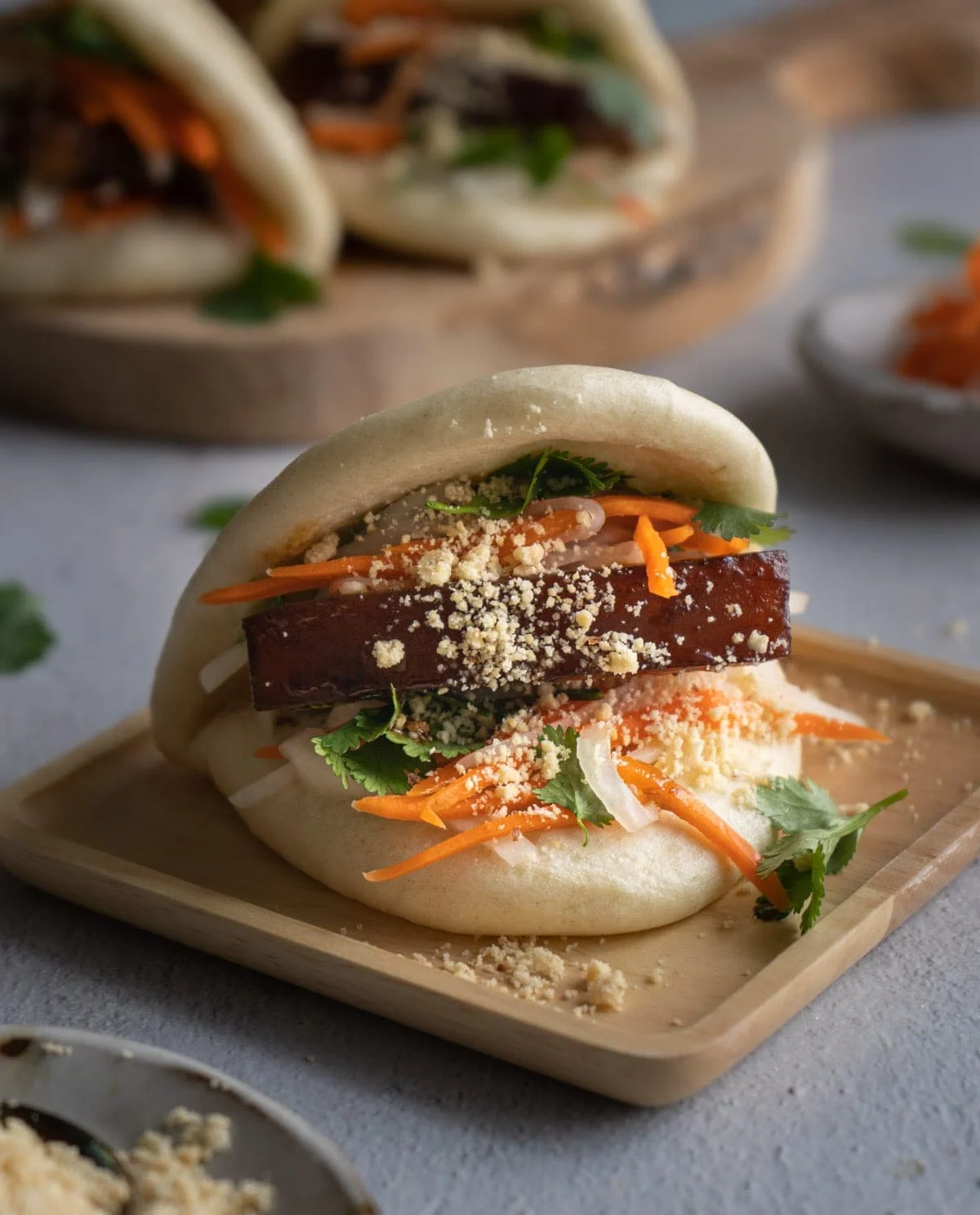 Thick slice of pork belly between a steamed bao bun with peanuts