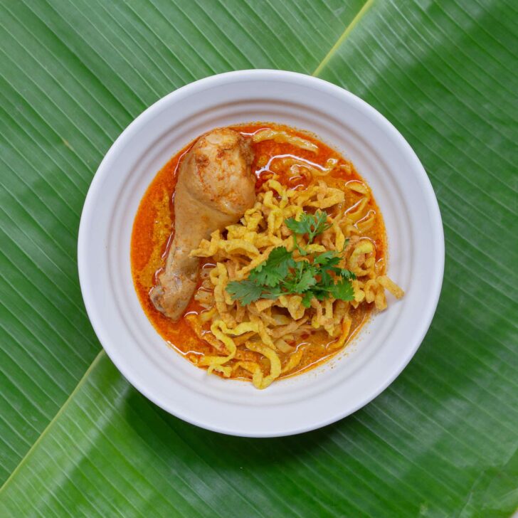 Khao soi with its vibrant red curry broth and crispy wonton noodles