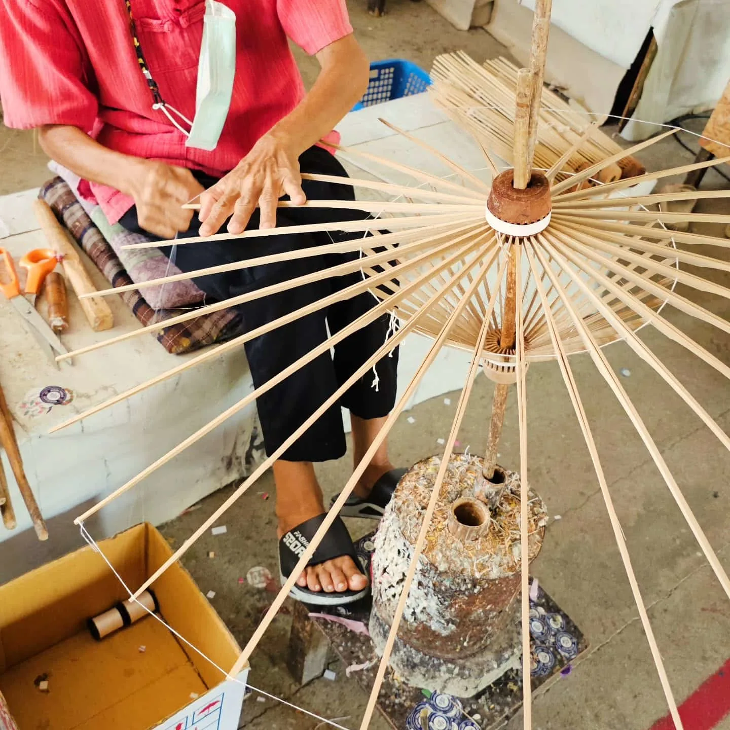 A local Thai lady at the umbrella making center constructing the structure