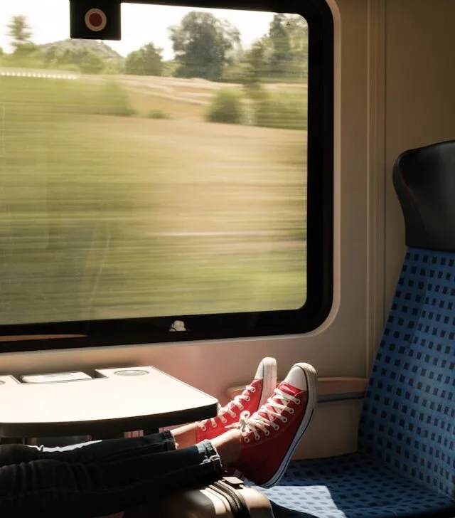 a person on a train with red and white trainers on a seat