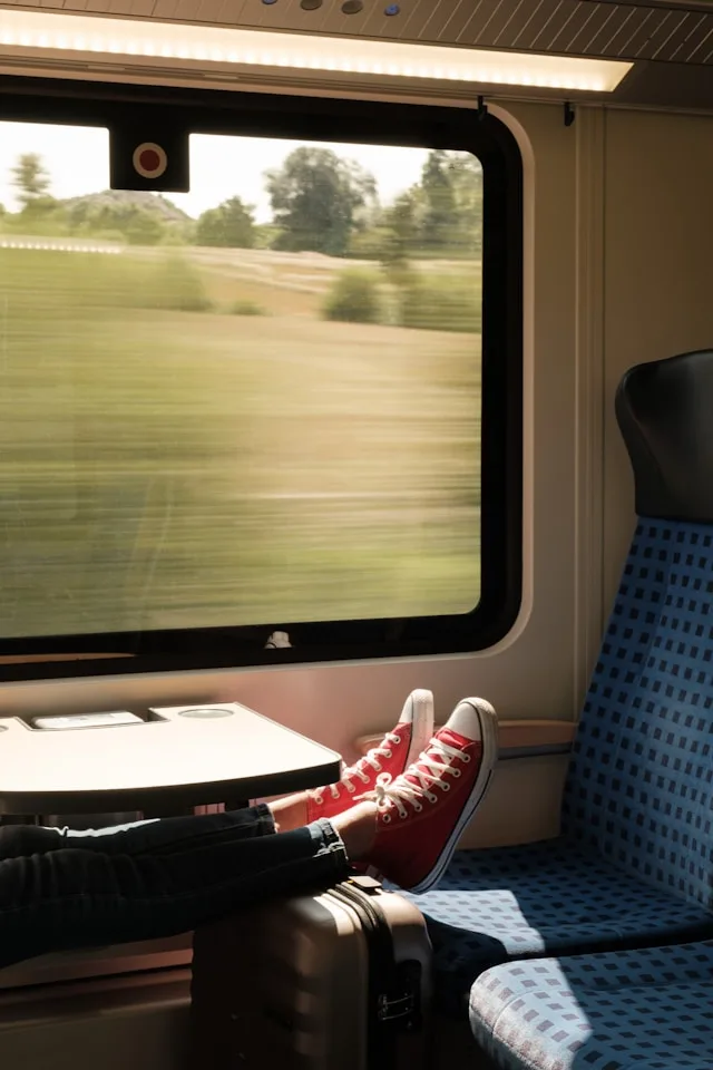 a person on a train with red and white trainers on a seat