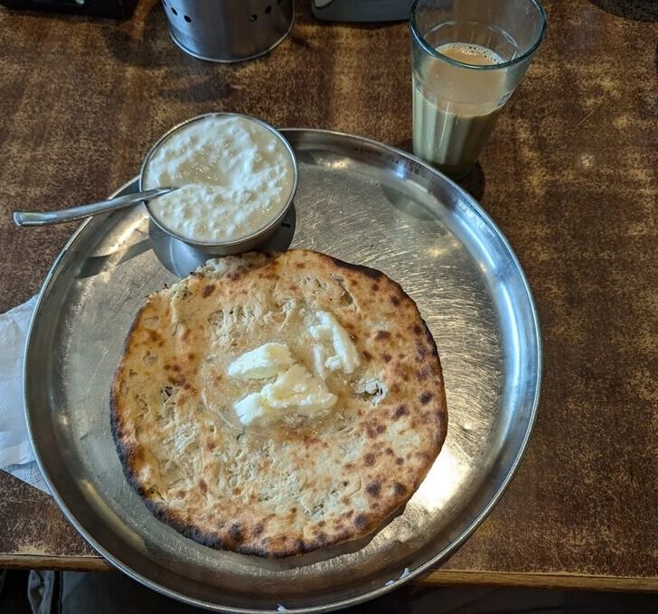 Metal thali plate containing aloo pharatha, a popular Indian breakfast food