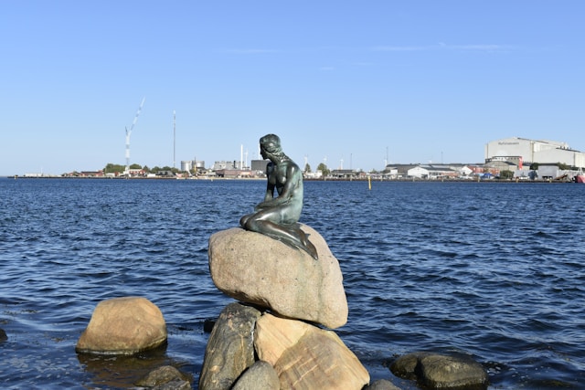a statue of the little mermaid overlooking water in copenhagen denmark