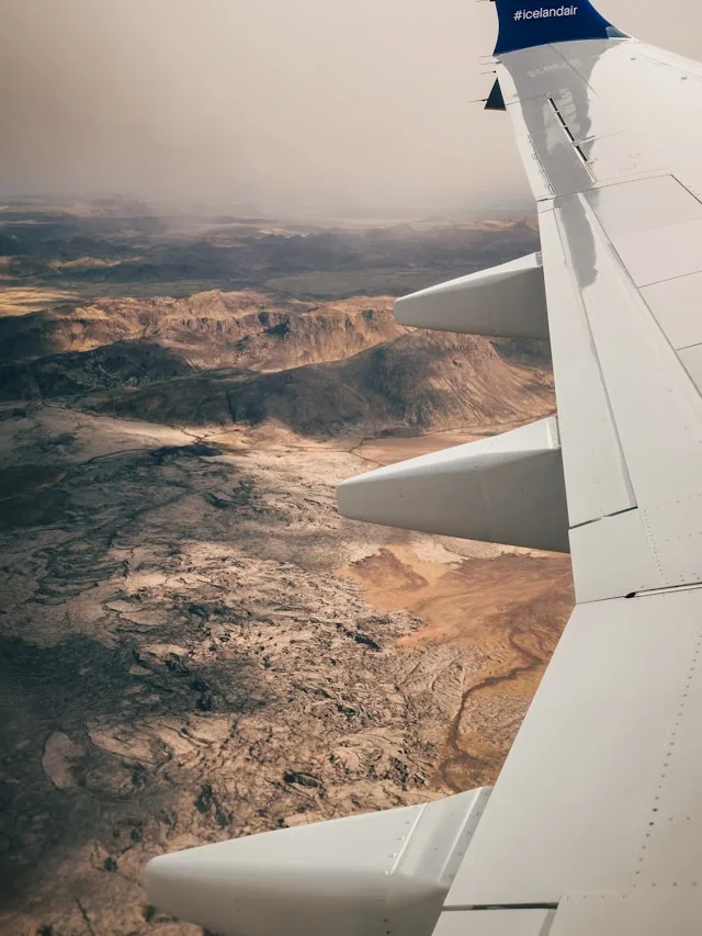 the wing of an icelandair airplane over a desert landscape